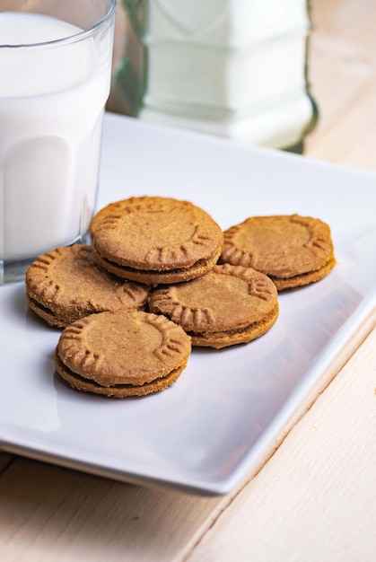 Close-up van een witte plaat met een stapel koekjes naast een glas melk Concept van zelfgemaakte ontbijtsnacks