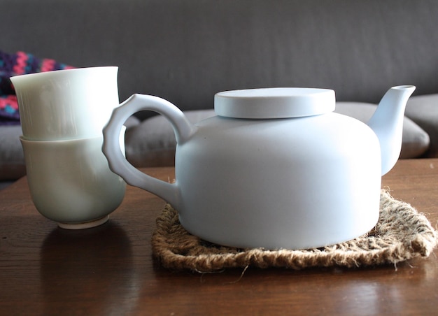Close-up van een witte theepot per kopje op tafel thuis