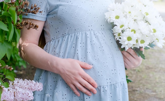 Close-up van een zwanger meisje in een zachtblauwe jurk met een foto van een echografisch onderzoek van een kind