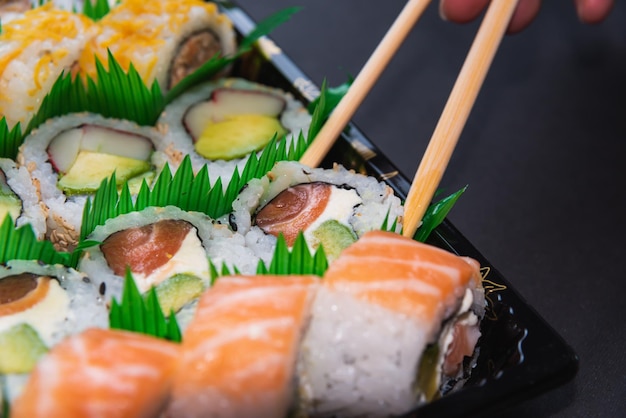 Close-up van eetstokjes die sushi uit een dienblad trekken