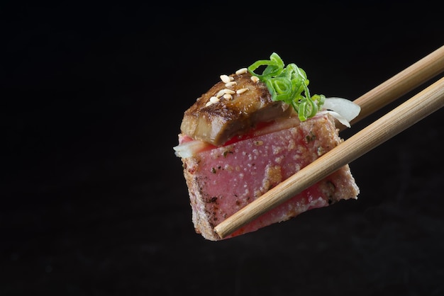 Close-up van eetstokjes met eten op een zwarte achtergrond