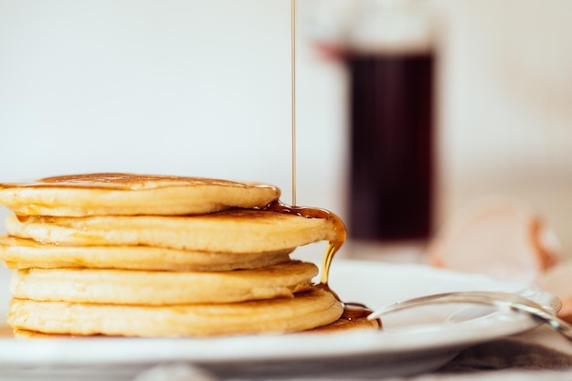 Foto close-up van esdoornstroop die op verse pannenkoeken valt