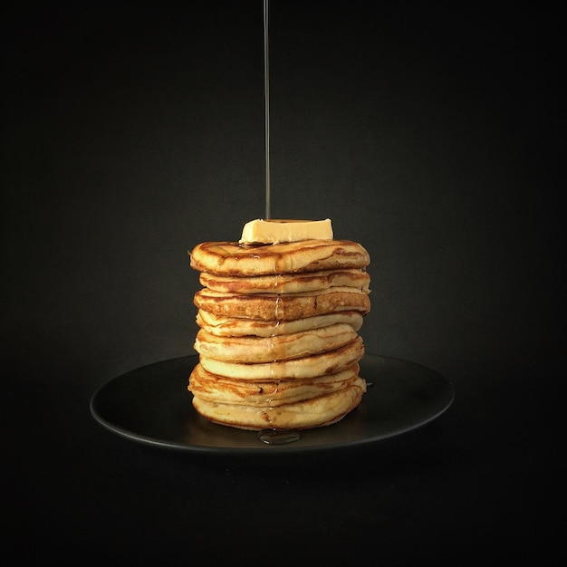 Close-up van esdoornstroop die over pannenkoeken stroomt
