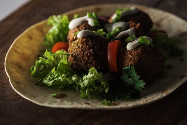 Close-up van falafel met saus op pitabroodje met groenten in het donker