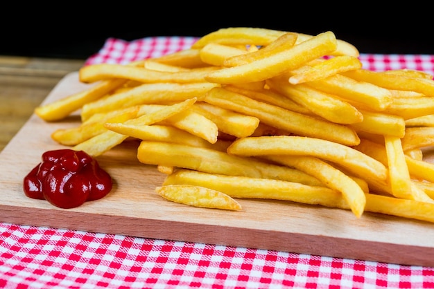 Close-up van frietjes met ketchup op tafel tegen een zwarte achtergrond