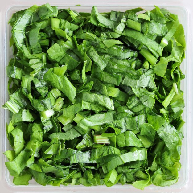 Close-up van gehakte groene bladerensalade in vierkante schotels textuur oppervlakteachtergrond