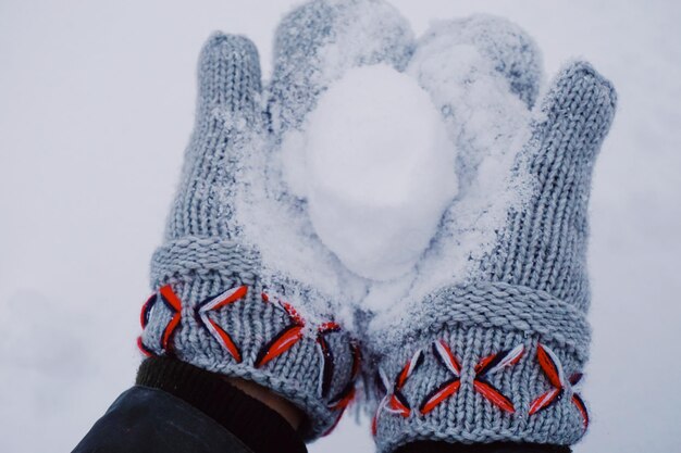 Close-up van gekapte handen die een sneeuwbal vasthouden