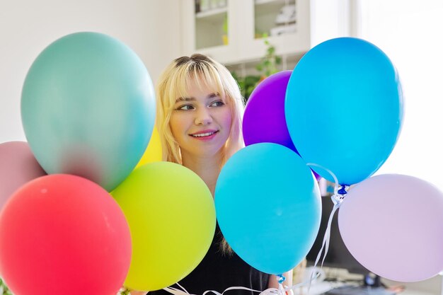 Close up van gekleurde ballonnen en blij lachend gezicht van blonde tiener vrouw