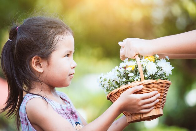 Foto close-up van geknipte handen die een bloemenmand geven aan een schattig meisje