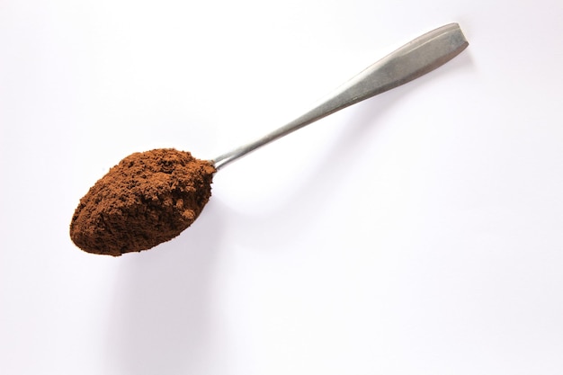 Close-up van gemalen koffie in een lepel op een witte achtergrond