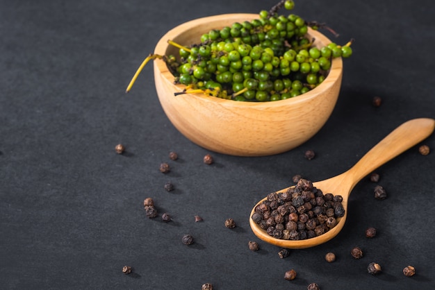 Close-up van gemalen zwarte peper in houten lepel op zwarte lijst