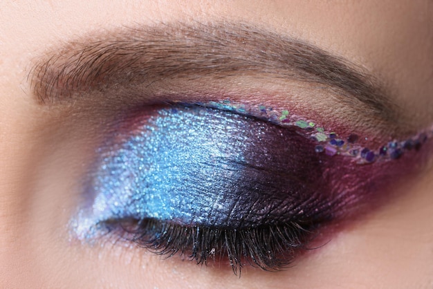 Close-up van gesloten vrouwelijk oog met helder paars make-up professioneel make-upconcept