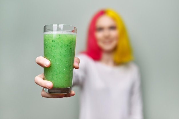 Close-up van glas met groene verse vitaminesmoothie in de hand van de vrouw