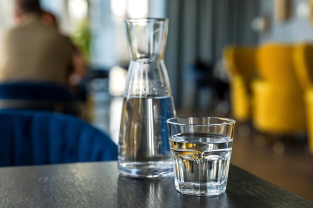 Close-up van glas water en karaf op tafel in café koffieshop sfeer op bokeh achtergrond