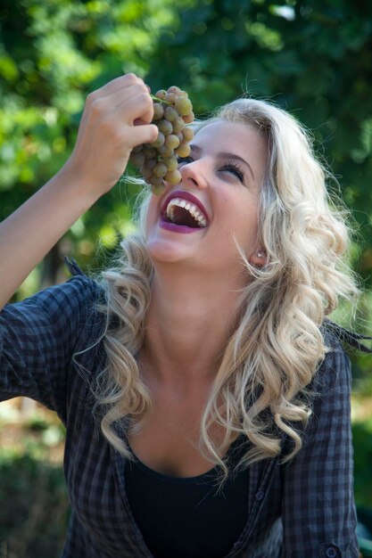 Foto close-up van glimlachende vrouw die druiven eet