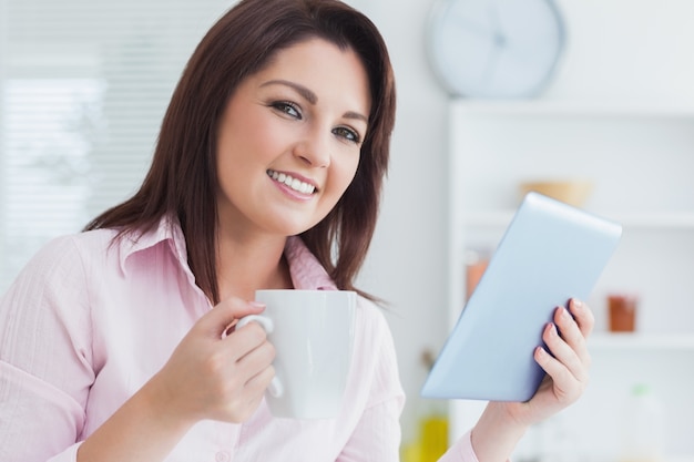 Close-up van glimlachende vrouw met koffiekop en digitale tablet