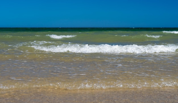 Close-up van golf van water op strand tegen achtergrond van heldere blauwe luchten op zomerdag