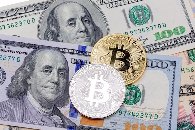 Close-up van gouden en zilveren bitcoin op honderd dollar ban