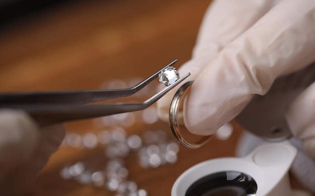 Foto close-up van goudsmidhand die kostbare ring met mooie diamanten verfraait