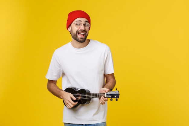 Close-up van grappige jonge man een gitaar spelen. geïsoleerd op geel goud