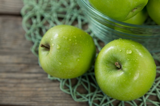 Close-up van groene appels met waterdruppeltjes in kom op houten kom