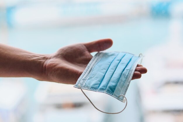 Close-up van hand die beschermend gezichtsmasker aanbiedt.