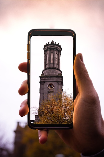 Foto close-up van hand die smartphone vasthoudt tegen de lucht