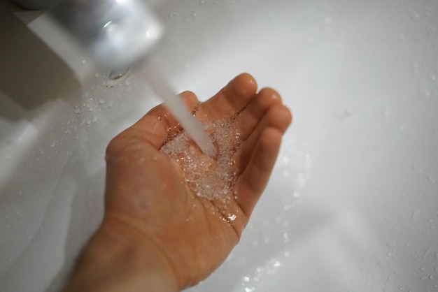 Close-up van hand die water aanraakt in de badkamer