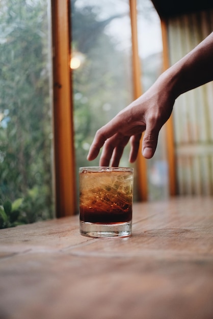 Close-up van hand over drankje in glas op tafel