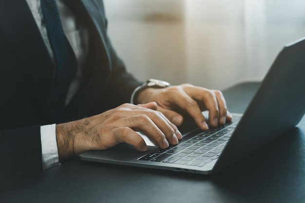 Close-up van hand zakenman dragen pak typen en werken op laptopcomputer op houten tafel thuiskantoor Ondernemer man aan het werk voor bedrijf thuiskantoor Werken technologie concept