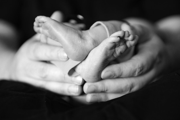 Foto close-up van handen die baby's voeten vasthouden