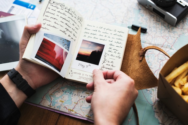 Foto close-up van handen die het notitieboekje van de reisagenda over kaartachtergrond houden