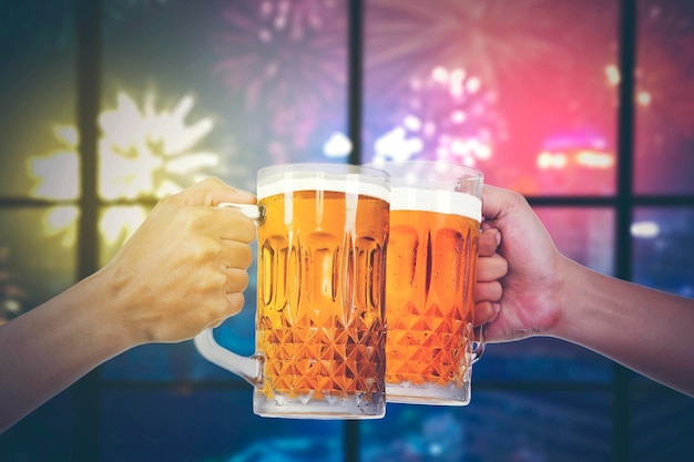 Close-up van handen die roosteren met flesjes bier in de feestclub met vuurwerk buiten
