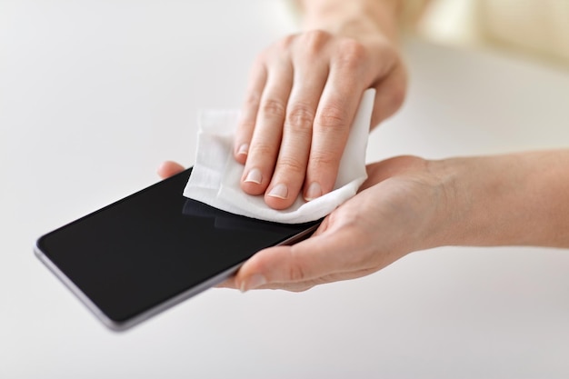 Close-up van handen die smartphone schoonmaken met een zakdoek