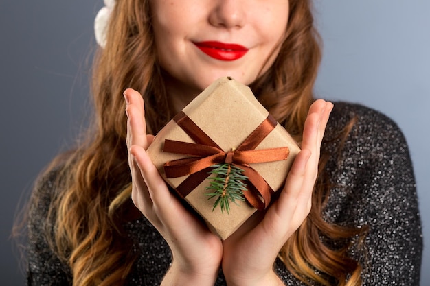 Close-up van handen en lippen geven een mooie geschenkdoos aan je vrouw die cadeau-cadeautjes geeft en het concept van het begroetingsseizoen op geïsoleerde grijze achtergrond