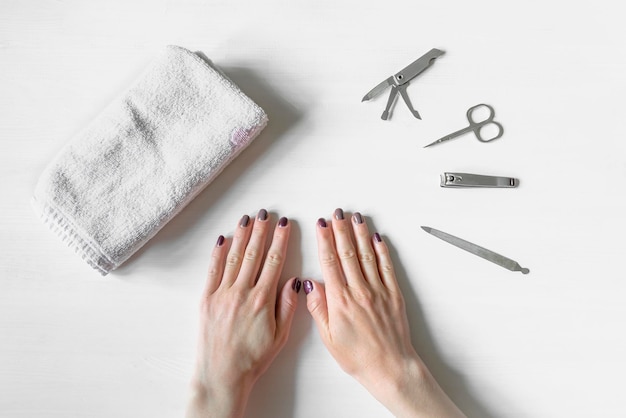 Close-up van handen met gepolijste nagels en manicure instrumenten. Jonge kaukasische vrouw die french manicure thuis of in de nagelsalon ontvangt. manicure, zelfverzorging, schoonheidsprocedures zelf