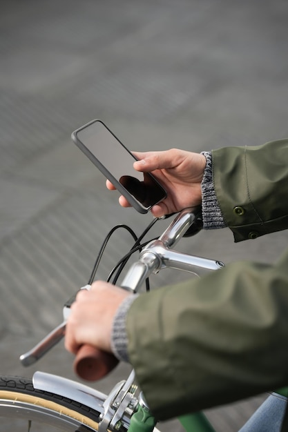 Close-up van handen met telefoon en stuur van de fiets