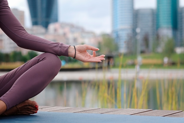 Close up van handen van jonge office yogi vrouw sittingriverbank in de stad, mediteren met vingers in Jnana mudra