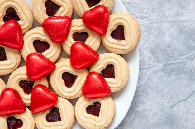 Close-up van hartvormige koekjes en chocolaatjes in rode wikkel op plaat Achtergrond bovenaanzicht kopieerruimte