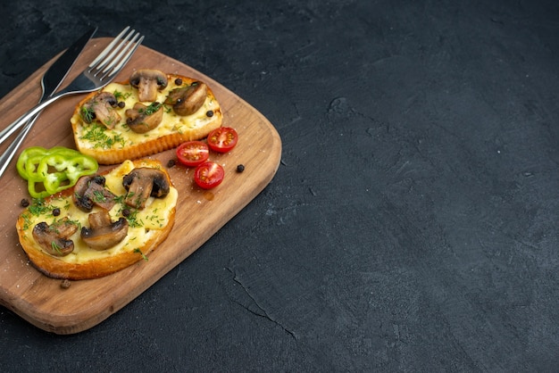 Close-up van heerlijke snacks met verse champignons en bestek op houten snijplank aan de rechterkant op zwarte achtergrond