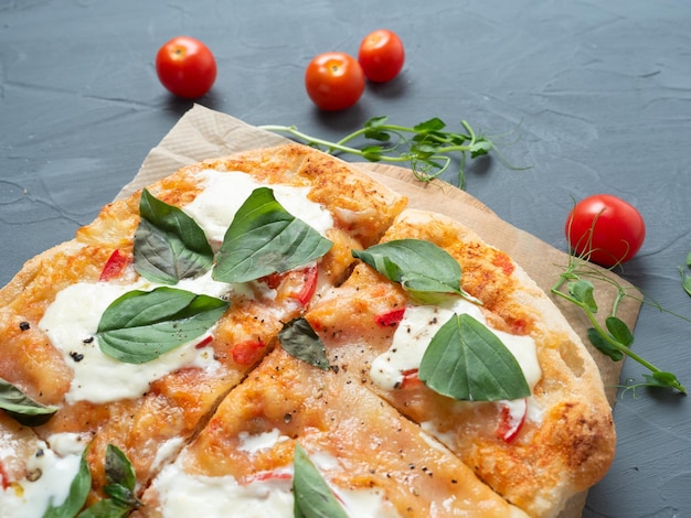 Close-up van heerlijke verse knapperige Romeinse pizza met kaas en kruiden op een grijze achtergrond Verse rijpe tomaten zijn in de buurt Kraftpapier Bovenaanzicht plat leggen