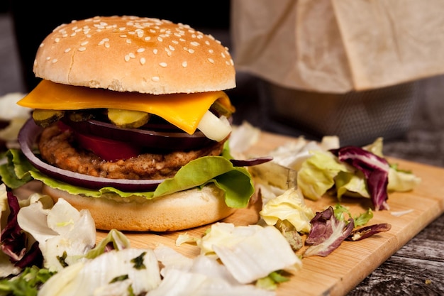 Close up van heerlijke zelfgemaakte hamburger op houten plaat naast frietjes. Fast food. Ongezond tussendoortje