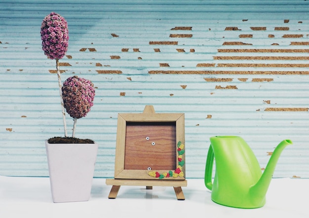Foto close-up van het beeldframe door potplant en waterpot op tafel tegen de muur