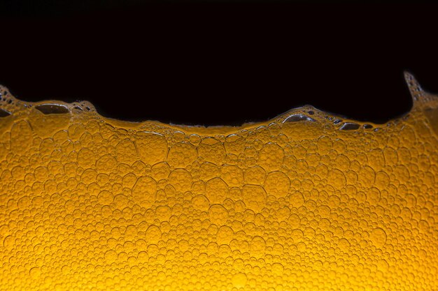 Close-up van het bier Close-up in schuim en bubbels van bier op zwarte achtergrond Waterdruppels achtergrond