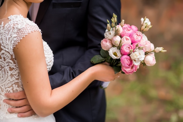 Close-up van het boeket van de bruid in haar handen. Fijne witte, roze en crèmekleurige rozen