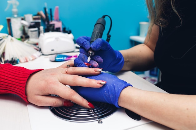 Close-up van het frezen van nagels in een schoonheidssalon Een vrouw krijgt een manicure voor haar nagels Schoonheidsspecialiste poetst de nagels van de klant