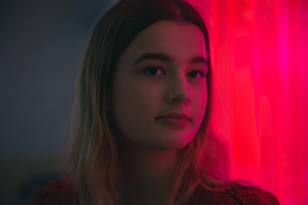 Close-up van het gezicht van een jonge vrouw in neon rood licht