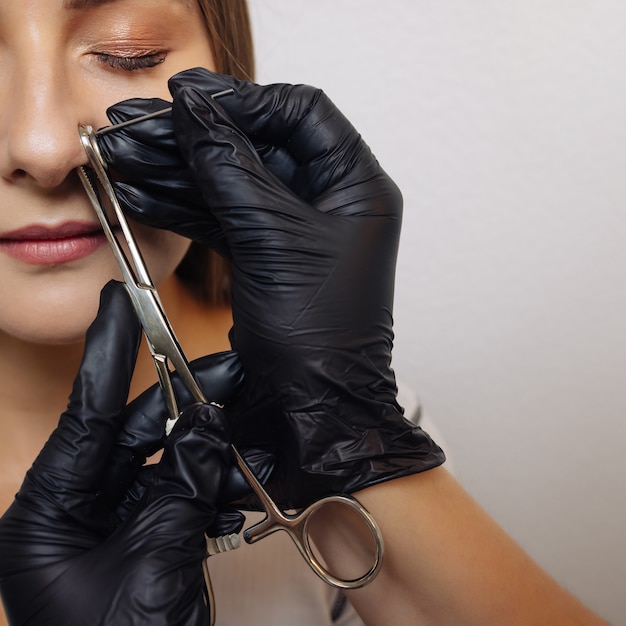 Close-up van het gezicht van een jonge vrouw met piercing die aan haar neus hangt.