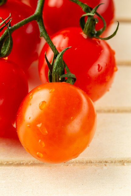 Close-up van het houten oppervlak en verse natte tomaten op de groene tak die er smakelijk uitzien