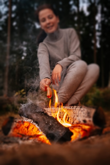 Close-up van het koken van vleesworsten in brand met mensen die op de achtergrond zitten Wandelen in het bos